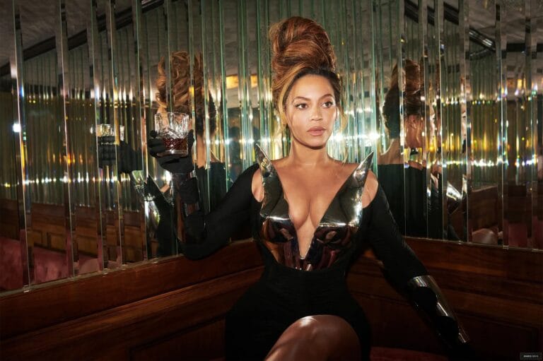 Beyoncé: Wears a fitted black dress with metallic details at the neckline that accentuate her…