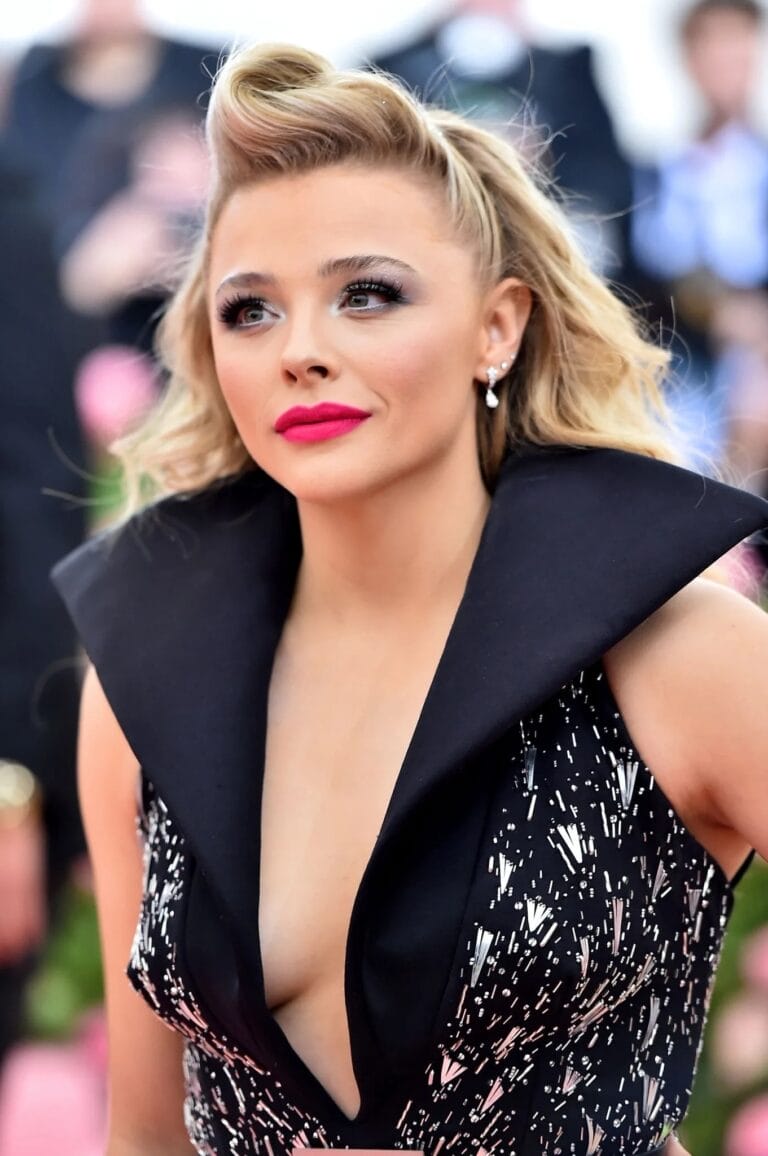 Chloë Grace Moretz: Wears a black dress with a deep V-neck and a striking…