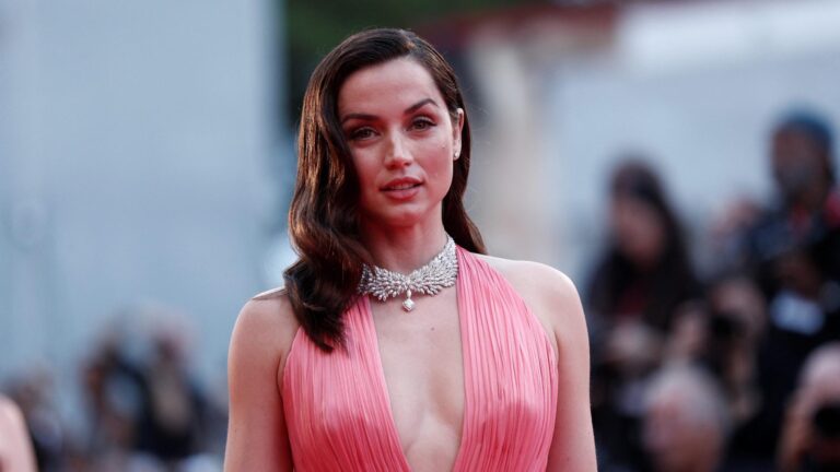 Ana de Armas: Wears a pink dress with a deep V-neck. Wears a silver necklace…