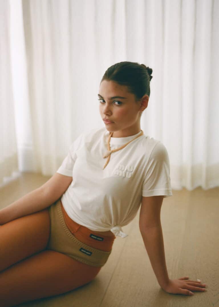 Ariana Greenblatt: Wears a white T-shirt with a small knot at the front and a necklace…