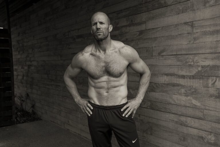 Jason Statham: Barefoot. Wearing dark sweatpants. No shirt and no accessories.
