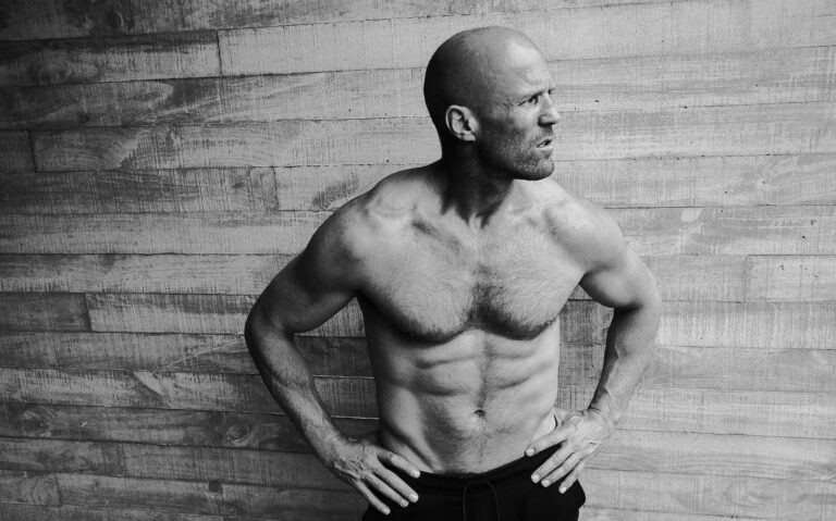 Jason Statham: Wearing dark pants, shirtless, with no visible shoes. Standing next to a...
