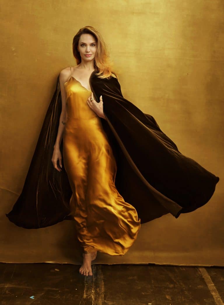 Angelina Jolie: Wearing a gold satin dress with thin straps and a black cape…