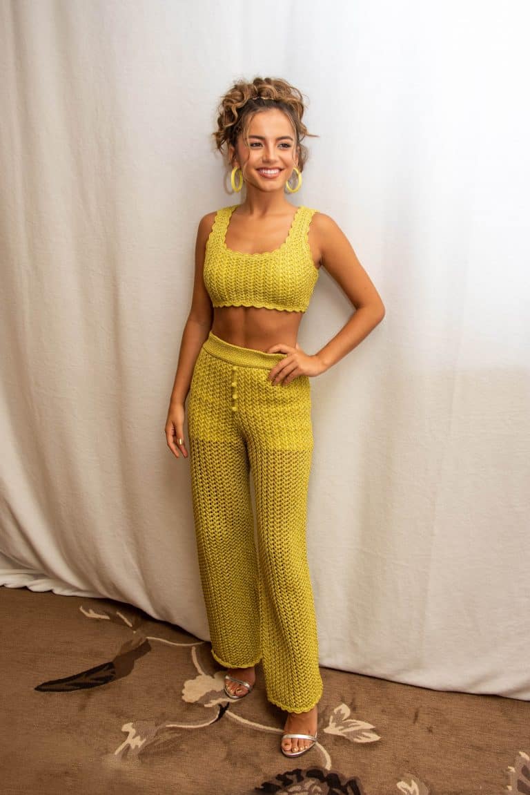 Isabela Merced: Smiling while wearing a yellow crochet set consisting of a top…