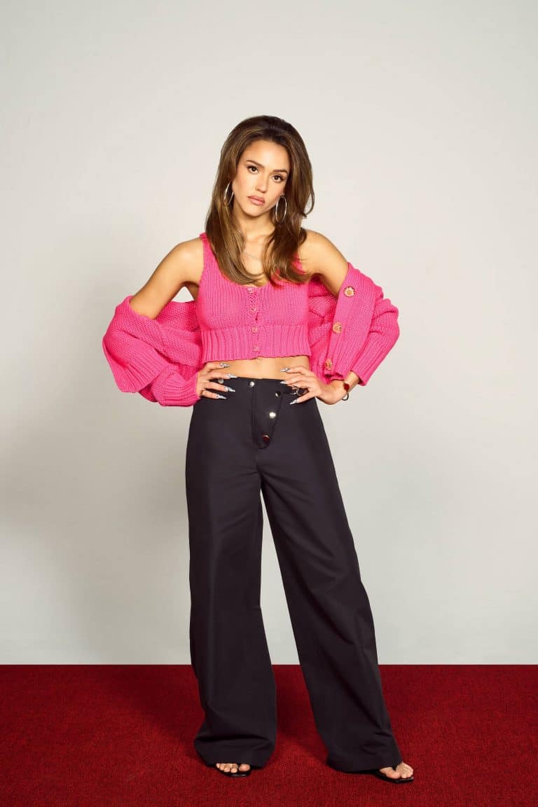 Jessica Alba: No lleva calzado visible. Viste un top y un cárdigan de punto rosado, con…