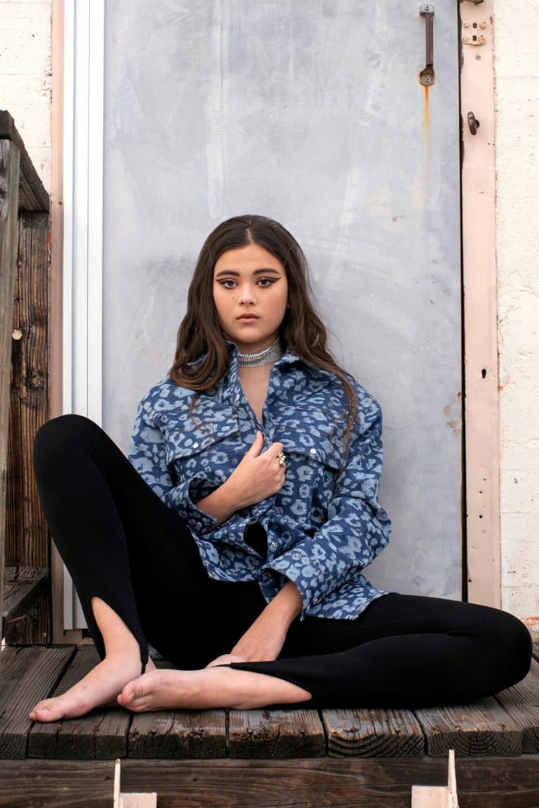 Lukita Maxwell: No lleva calzado. Viste una camisa de mezclilla azul con estampado, leggings negros y…