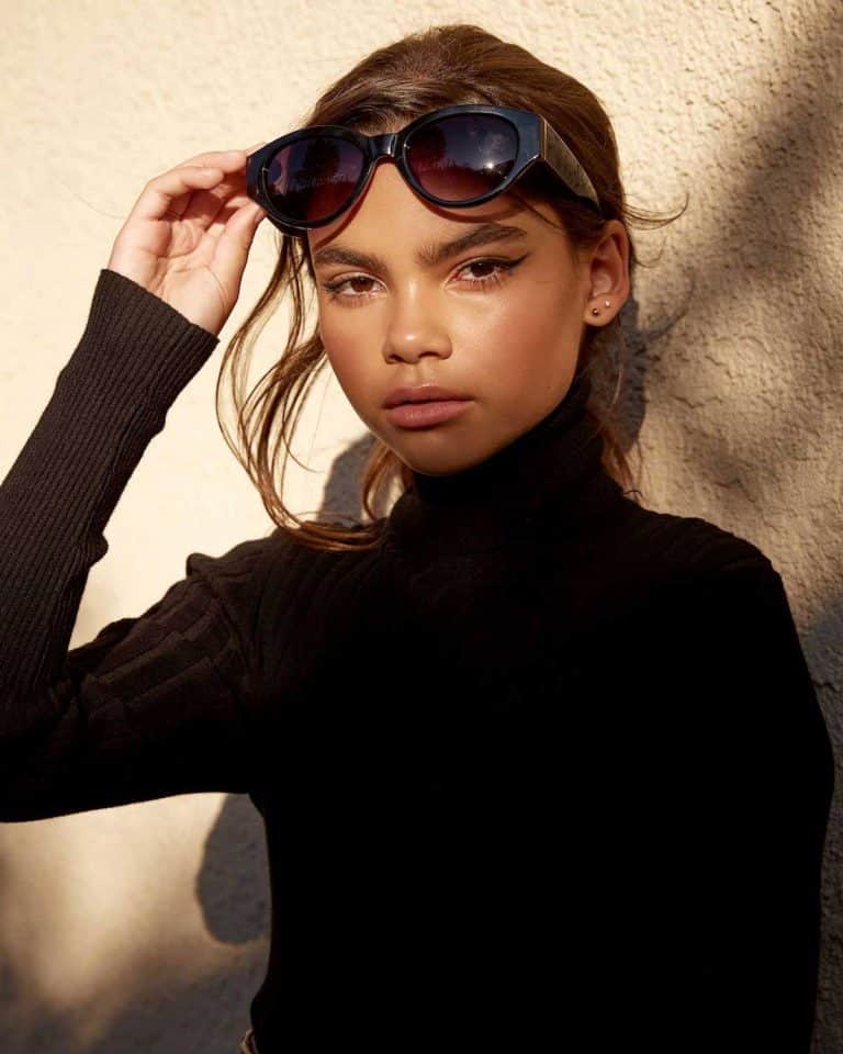 Ariana Greenblatt: Wears a black turtleneck sweater and large dark sunglasses.…