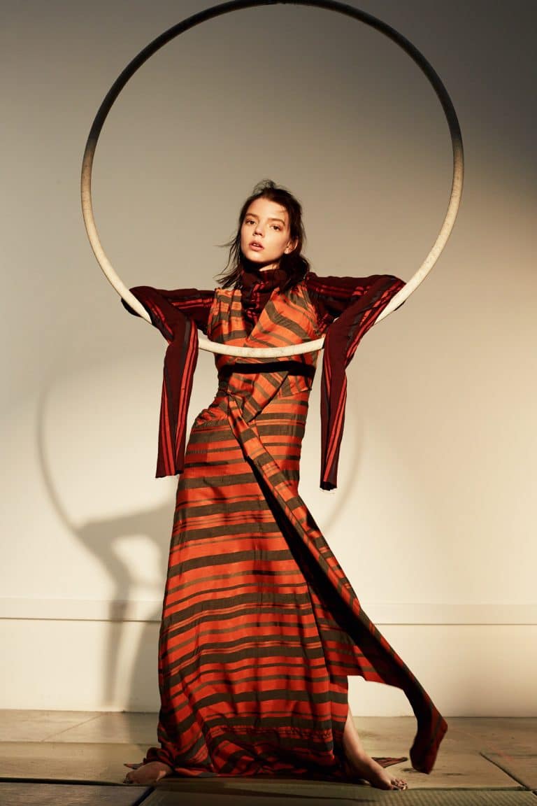 Anya Taylor-Joy: Wears a long dress with horizontal orange and brown stripes, with sleeves…