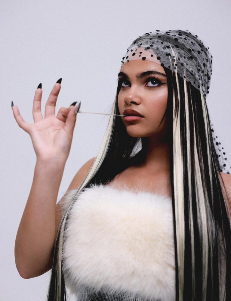 Ariana Greenblatt: Wears a sheer scarf with black polka dots on her head and a top with…