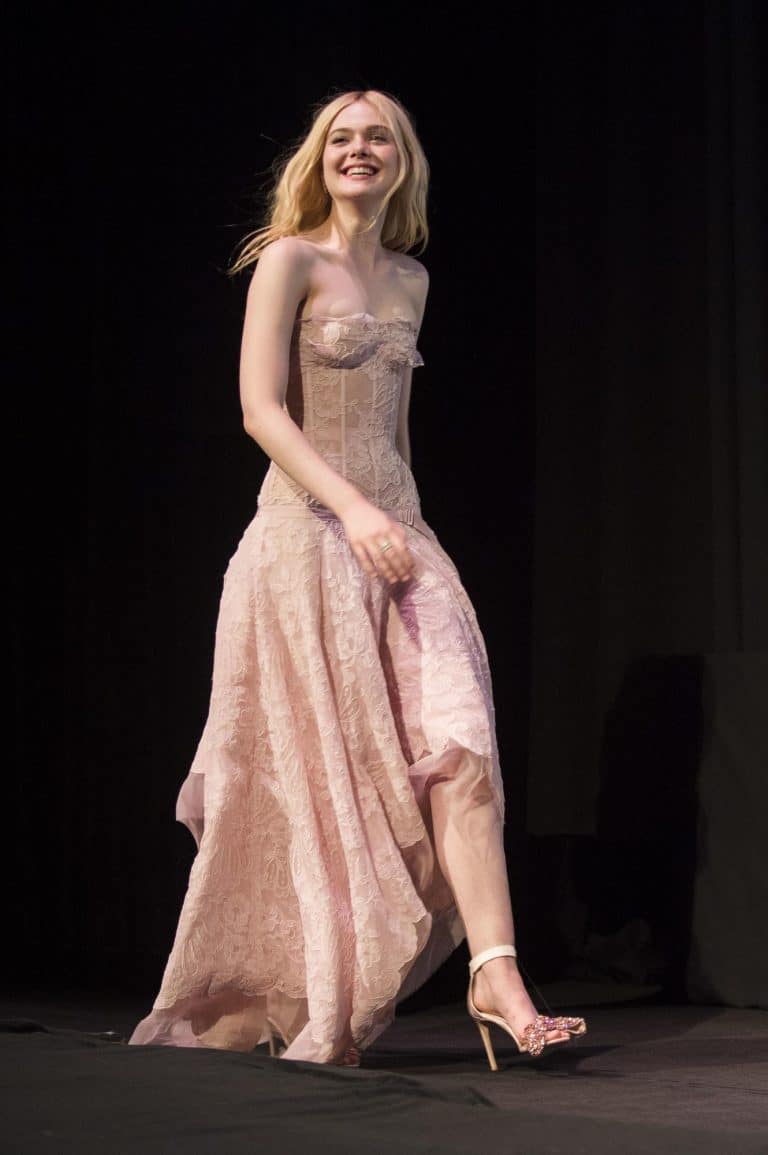 Elle Fanning: Lleva un vestido largo de encaje en tono rosa claro, con un corpiño ajustado…