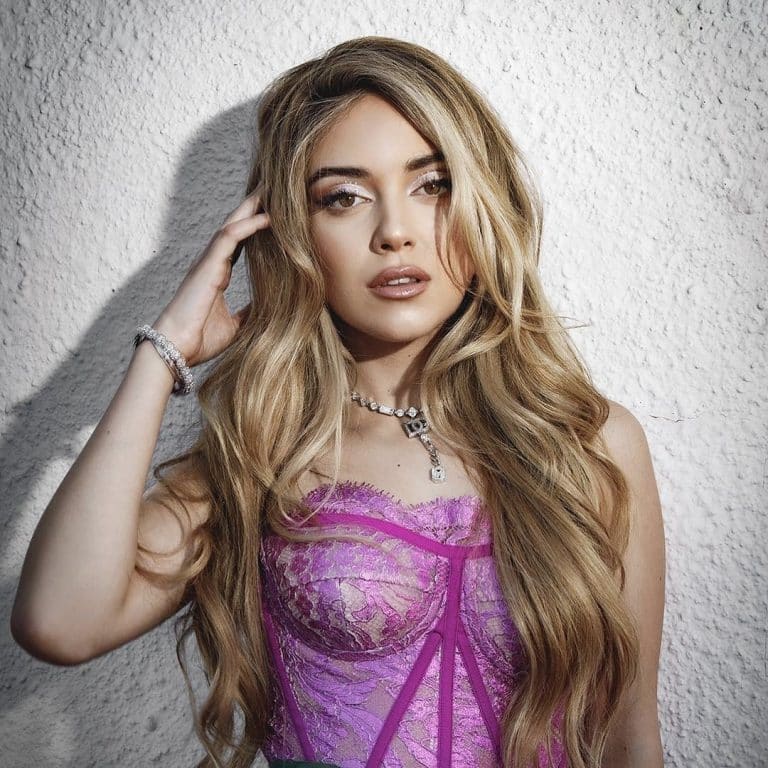 Ana Mena: The image shows a bright pink lace corset with lilac details.…