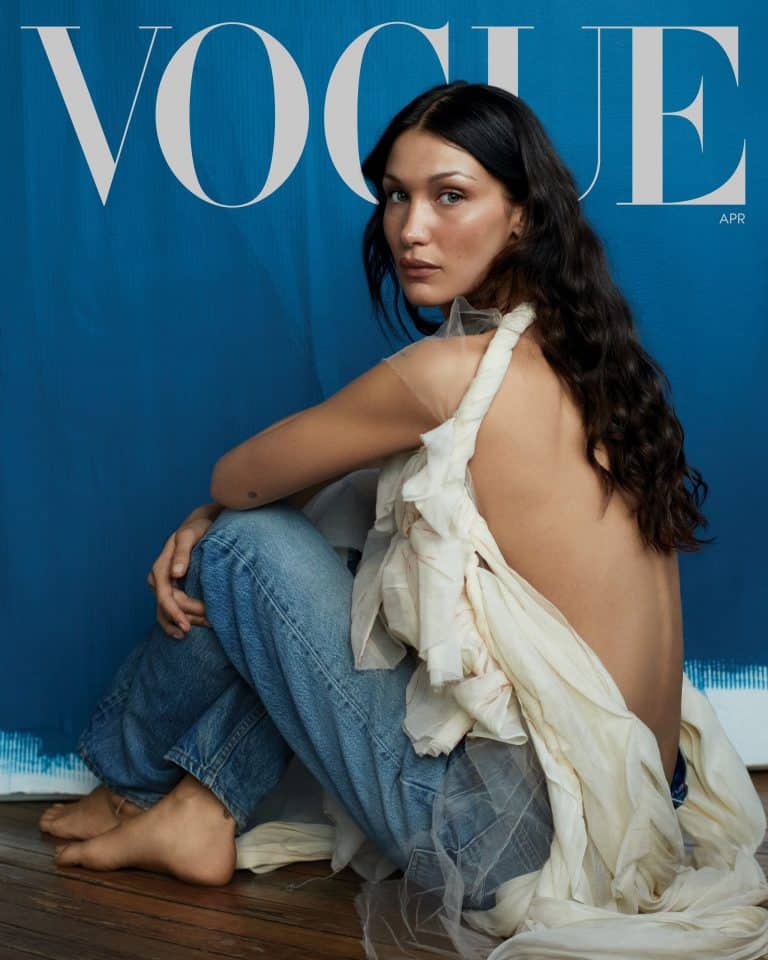 Bella Hadid: Long, loose dark hair. Wears a white lightweight fabric top…