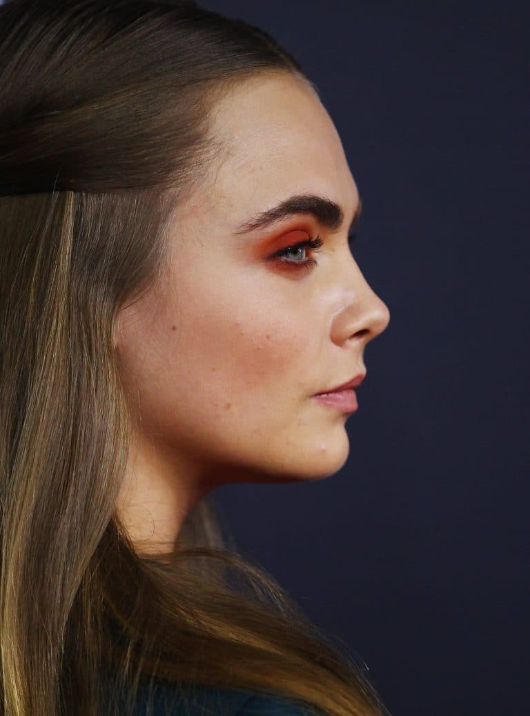 Cara Delevingne: Long, straight hair and bold makeup with orange tones on the eyes. The…