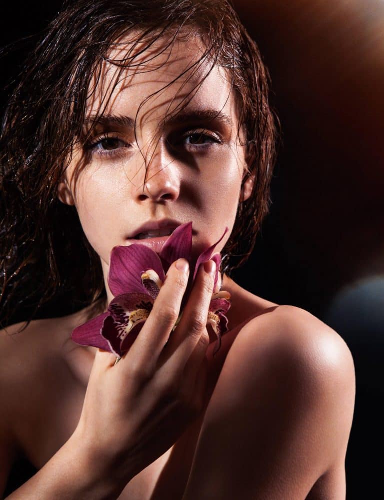 Emma Watson: Primer plano, con el pelo mojado y sosteniendo una flor sobre su boca.
