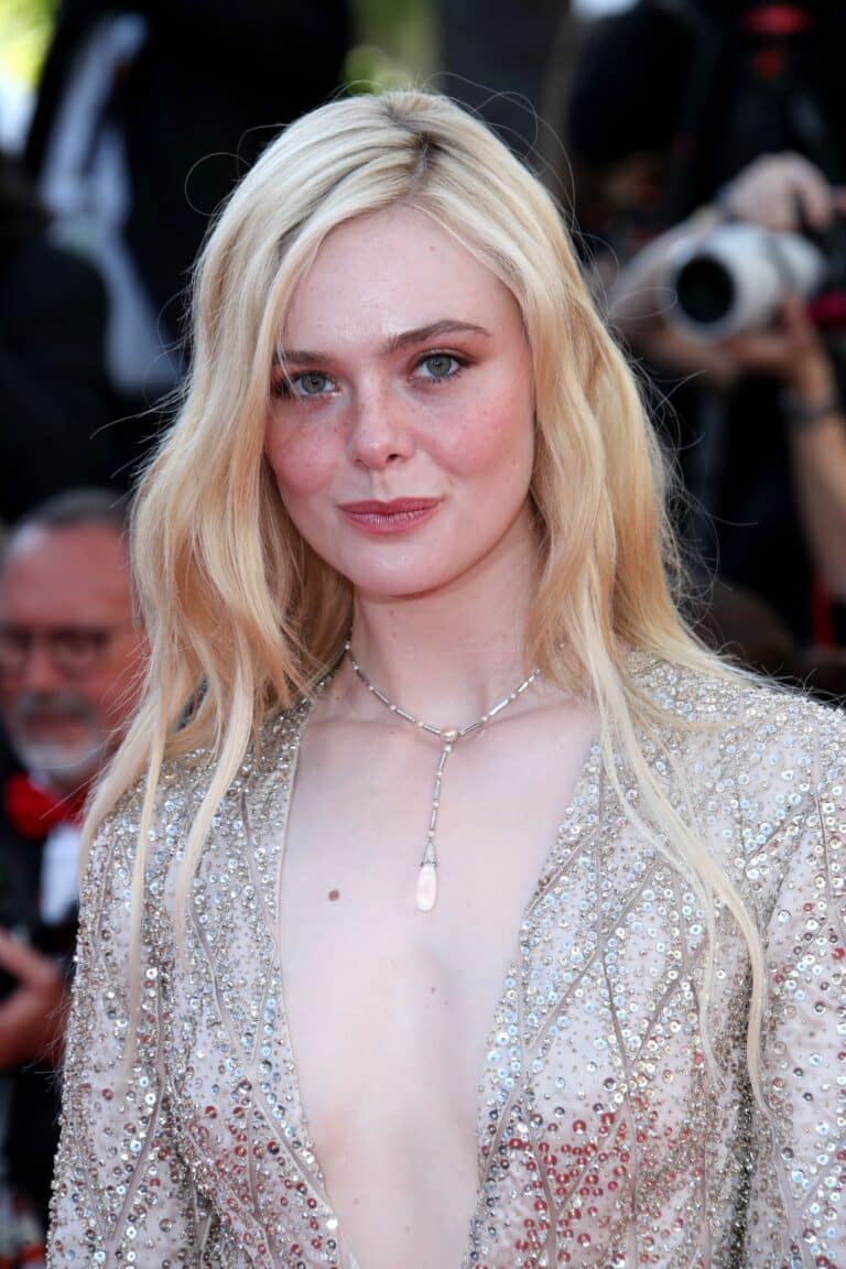 Elle Fanning: Loose blonde hair, wearing a shiny dress decorated with silver sequins and a…