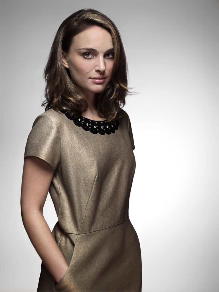 Natalie Portman: Wears an elegant gold dress with a black decorative collar. Her hair is loose…