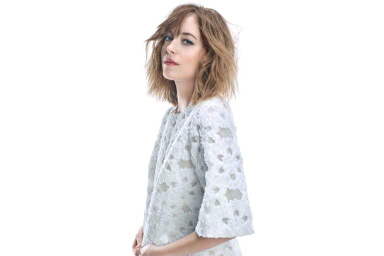 Dakota Johnson: Her hair is loose and wavy. She wears a white lace dress with a…