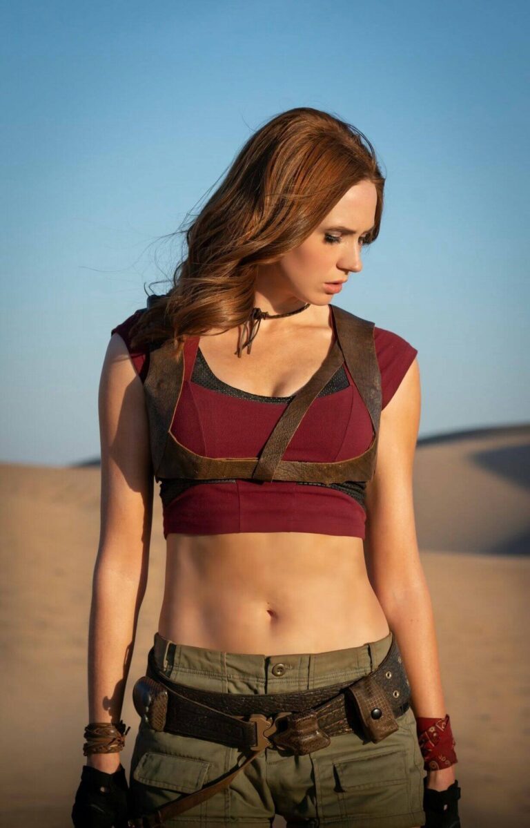 Karen Gillan: Wears a dark red top with black details and a brown harness. Pairs…