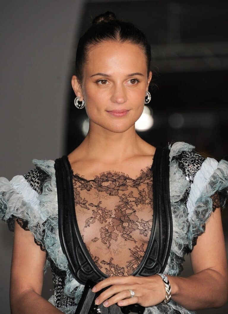 Alicia Vikander: Wears an elegant dress with black lace and chest details, paired with…