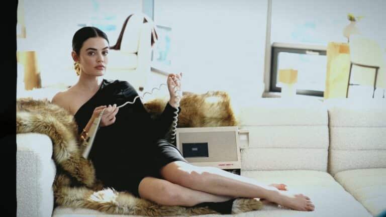Lucy Hale: Seated on a soft white sofa, wearing a black dress of a…