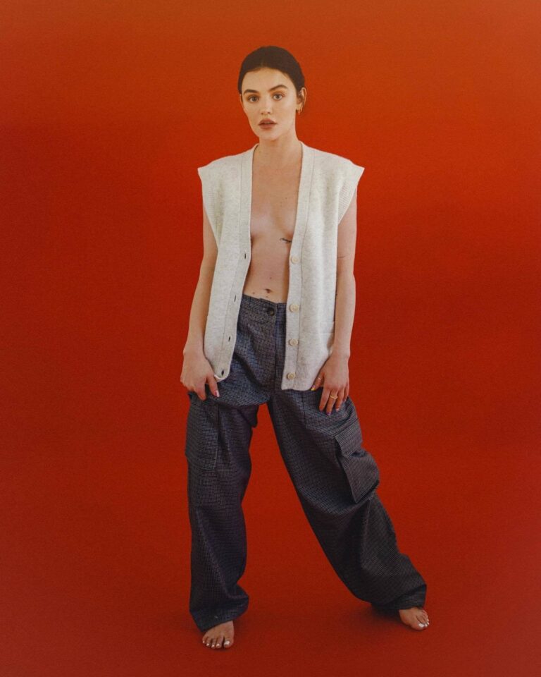 Lucy Hale: Wears a white vest with no shirt and wide dark pants. Is barefoot…