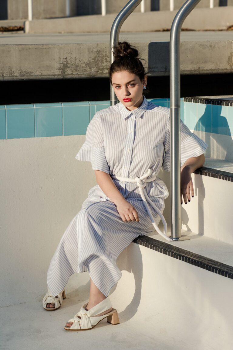 Odeya Rush: Wears a light blue and white striped dress with a matching belt.…