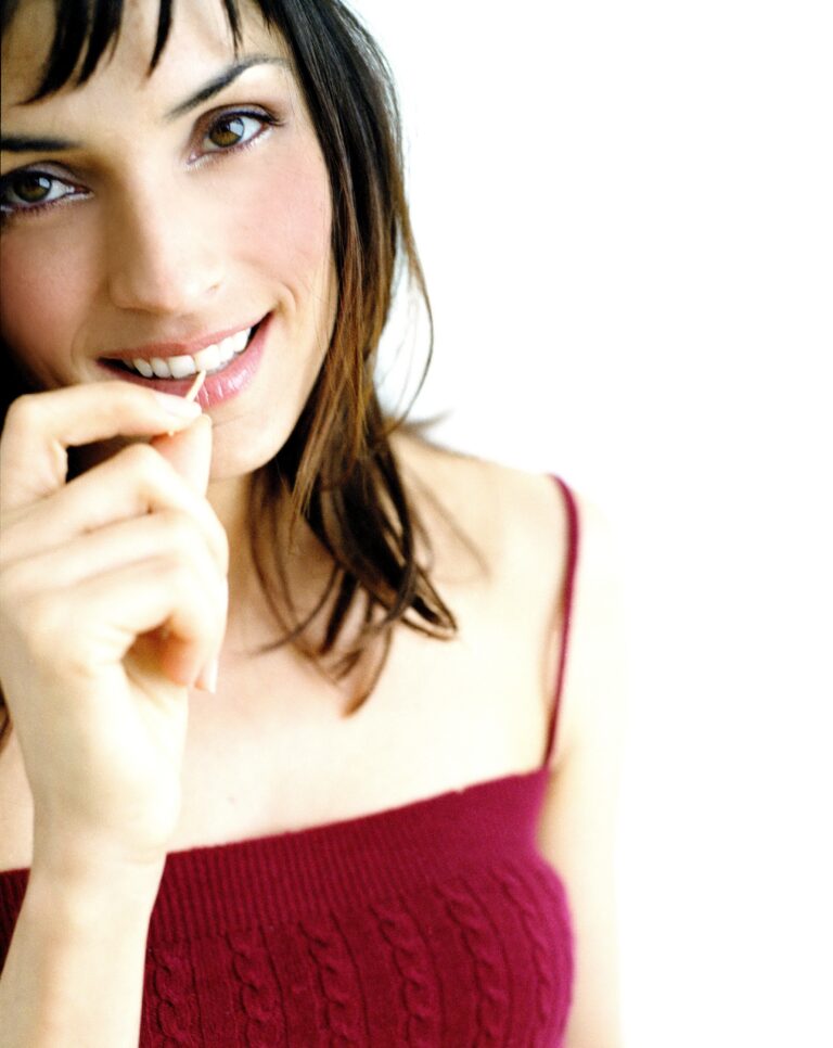 Famke Janssen: Wears a red braided-strap top. Her hair is dark…