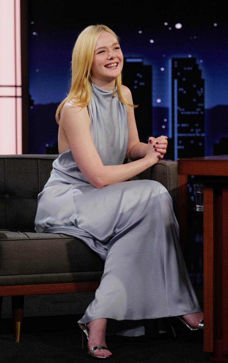 Elle Fanning: Wearing a long blue-gray dress, sleeveless with a high neck…