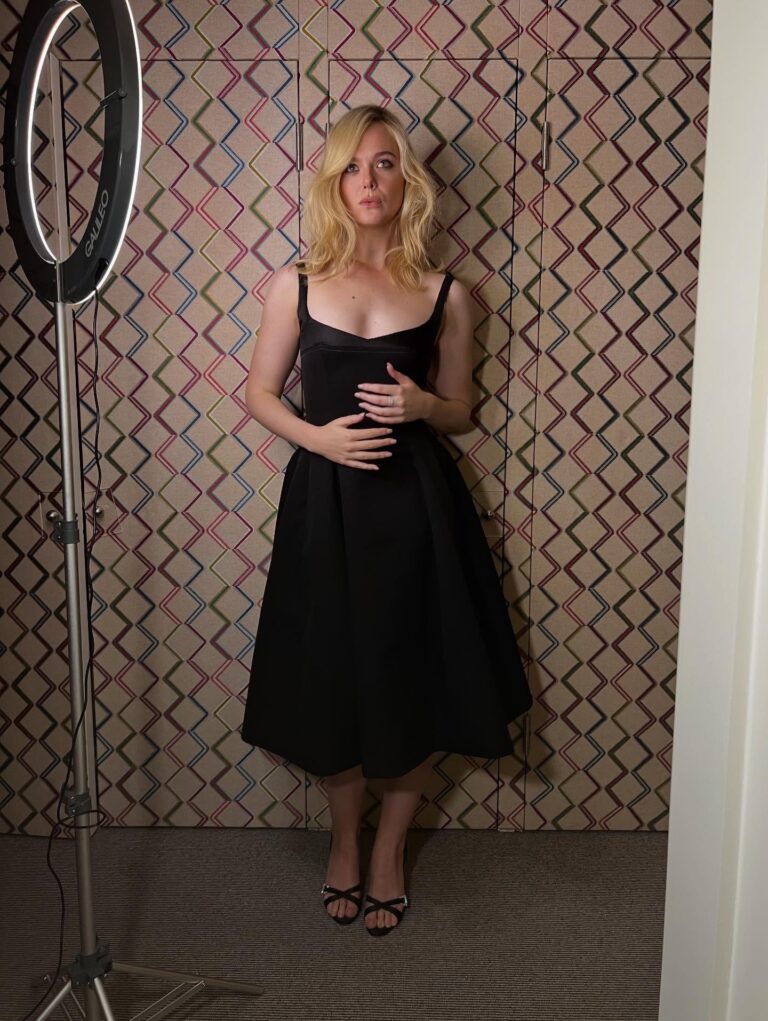 Elle Fanning: Wearing an elegant black slip dress with black heeled sandals that…