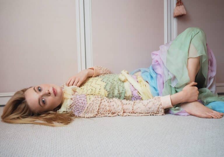 Elle Fanning: Lying on a rug, wearing a pastel dress with…