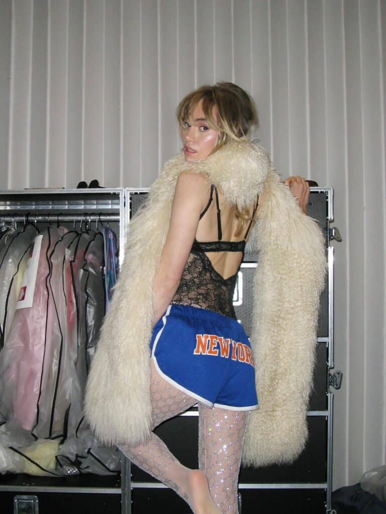 Suki Waterhouse: Luces un chaleco de encaje negro y unos shorts deportivos azules con la palabra…