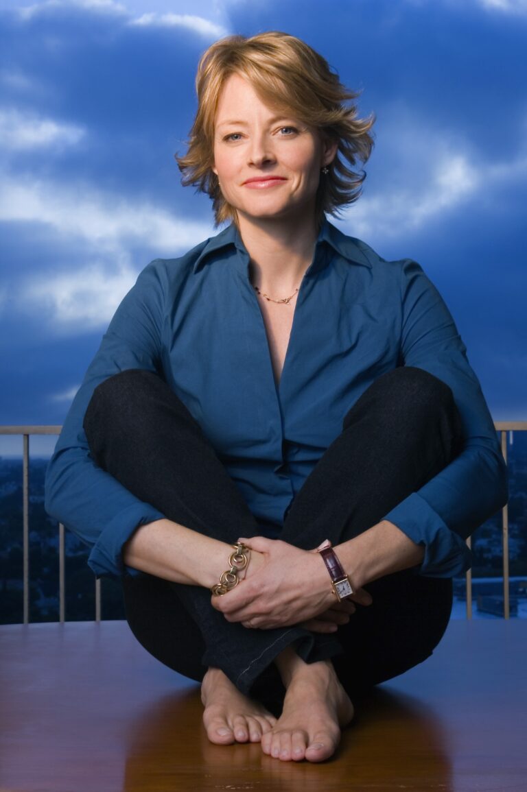 Jodie Foster: Wearing a blue shirt and dark pants. Wears a watch on the left wrist…