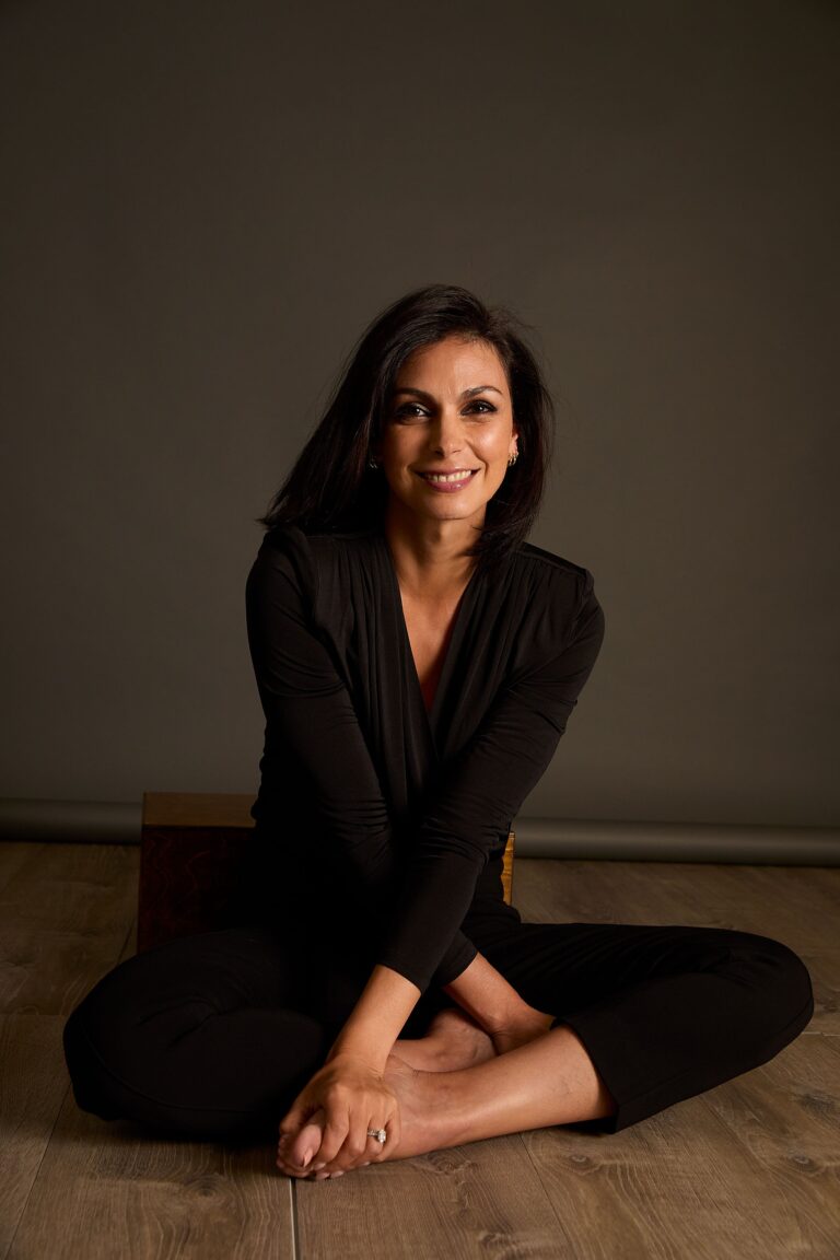 Morena Baccarin: Wears an all-black outfit with a long-sleeve top. Sitting on a…