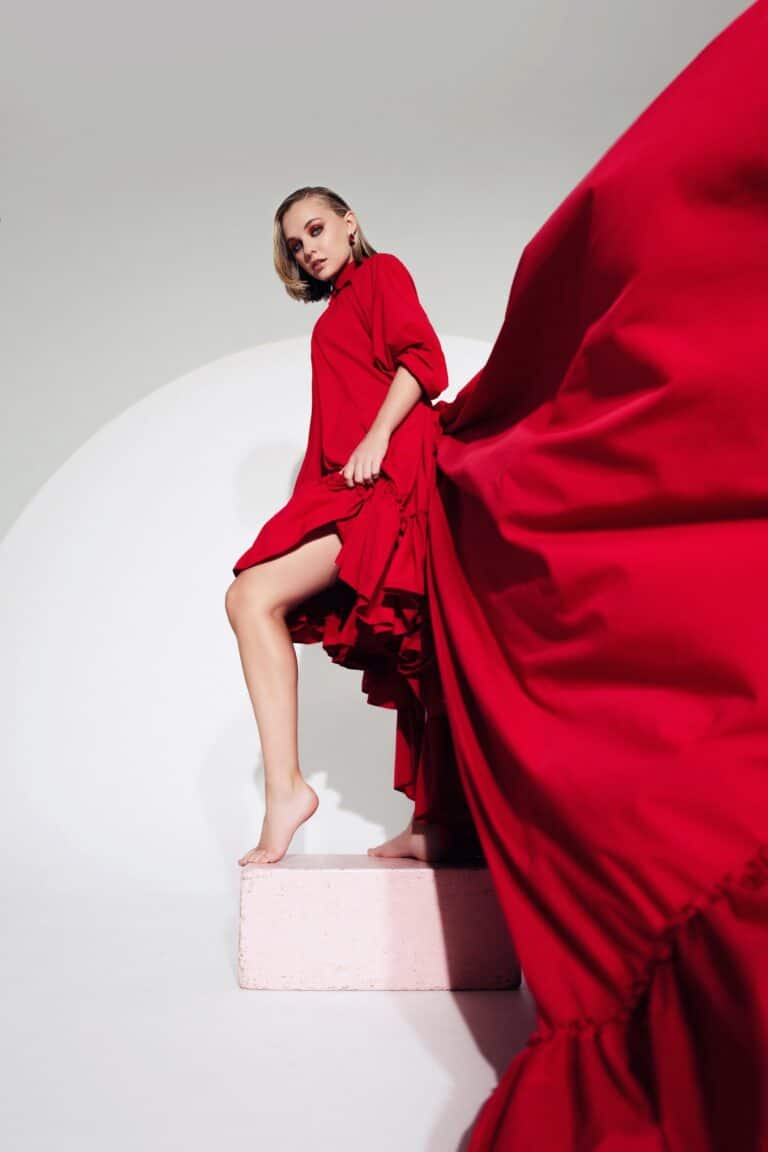 Madison Iseman: Long red dress with a voluminous, flowing design. Wears striking earrings and…