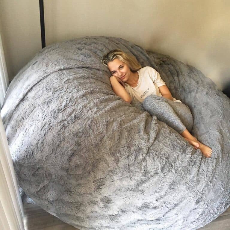 Madison Iseman: Sitting comfortably on a large gray beanbag, wearing a light T-shirt with the word…