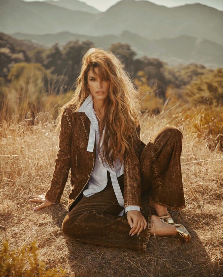 Cindy Crawford: Long, loose hair with tousled waves. Wearing a brown outfit with a velvet-textured…
