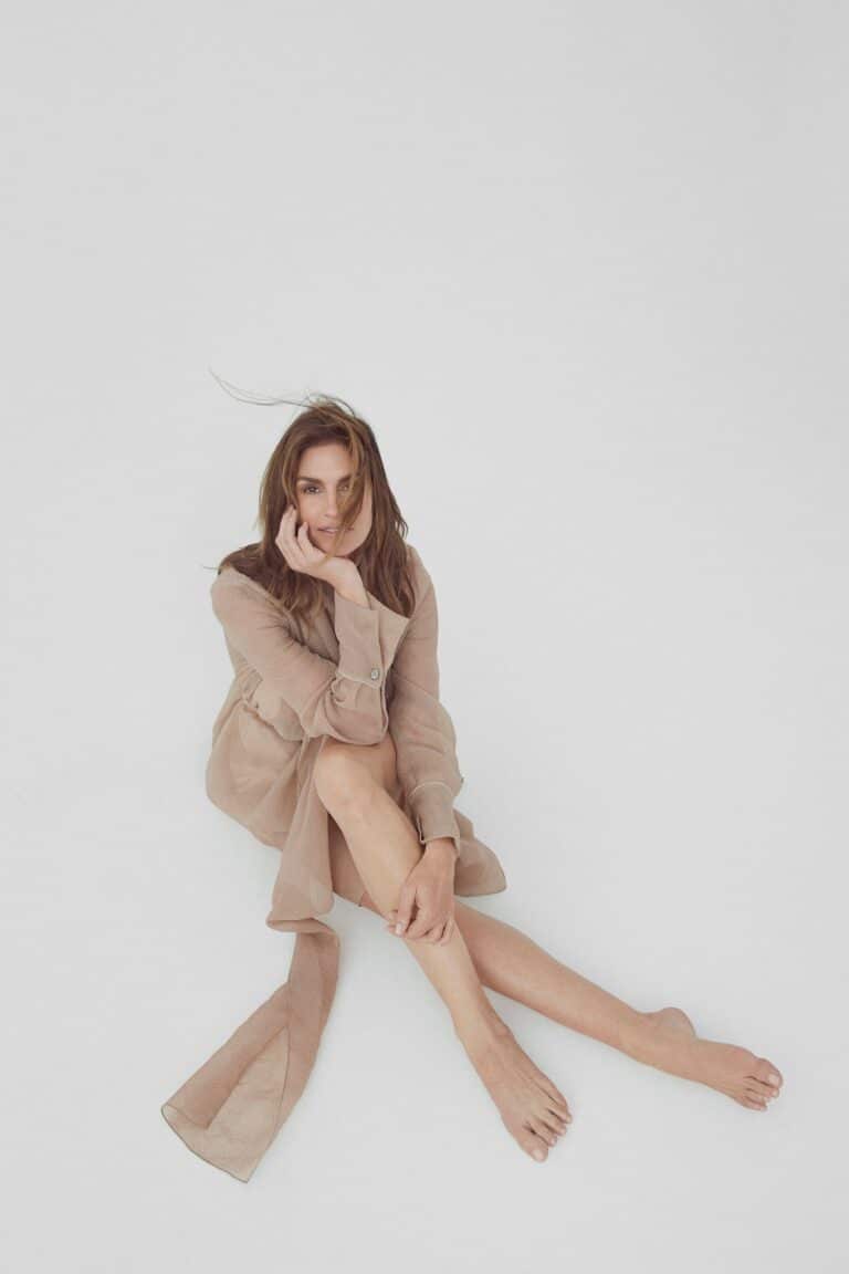 Cindy Crawford: Wears a long beige dress in a lightweight fabric, with long sleeves and…