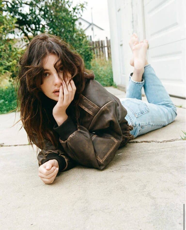 Camila Morrone: Wears a dark brown coat over a T-shirt, paired with light jeans. Barefoot,…
