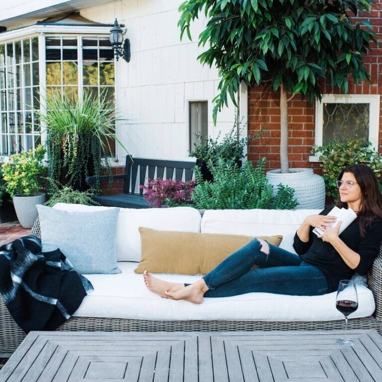 Tiffani Thiessen: Relajada en un sofá al aire libre, lleva una prenda negra de manga larga…