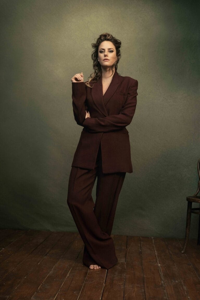 Kaya Scodelario: Wears a burgundy jacket and wide-leg pants suit, with her hair styled with…