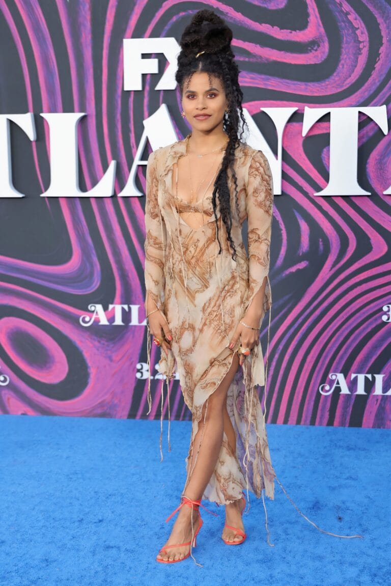 Zazie Beetz: Wears a long light-colored dress with brown details and a design…