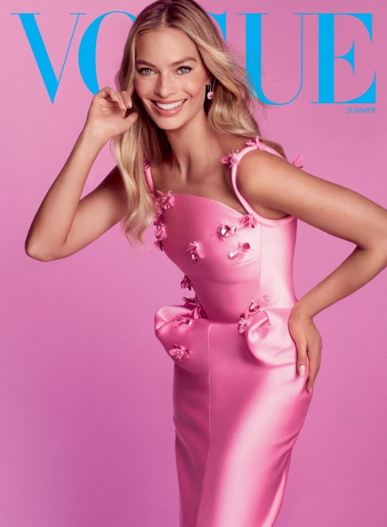 Margot Robbie: Pink dress with floral appliqués on the straps and waist, with a fitted design. Wears…