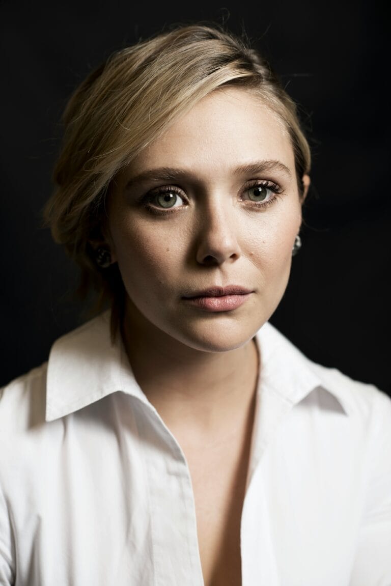 Elizabeth Olsen: Wears a white collared shirt. Blonde, short hair, styled…