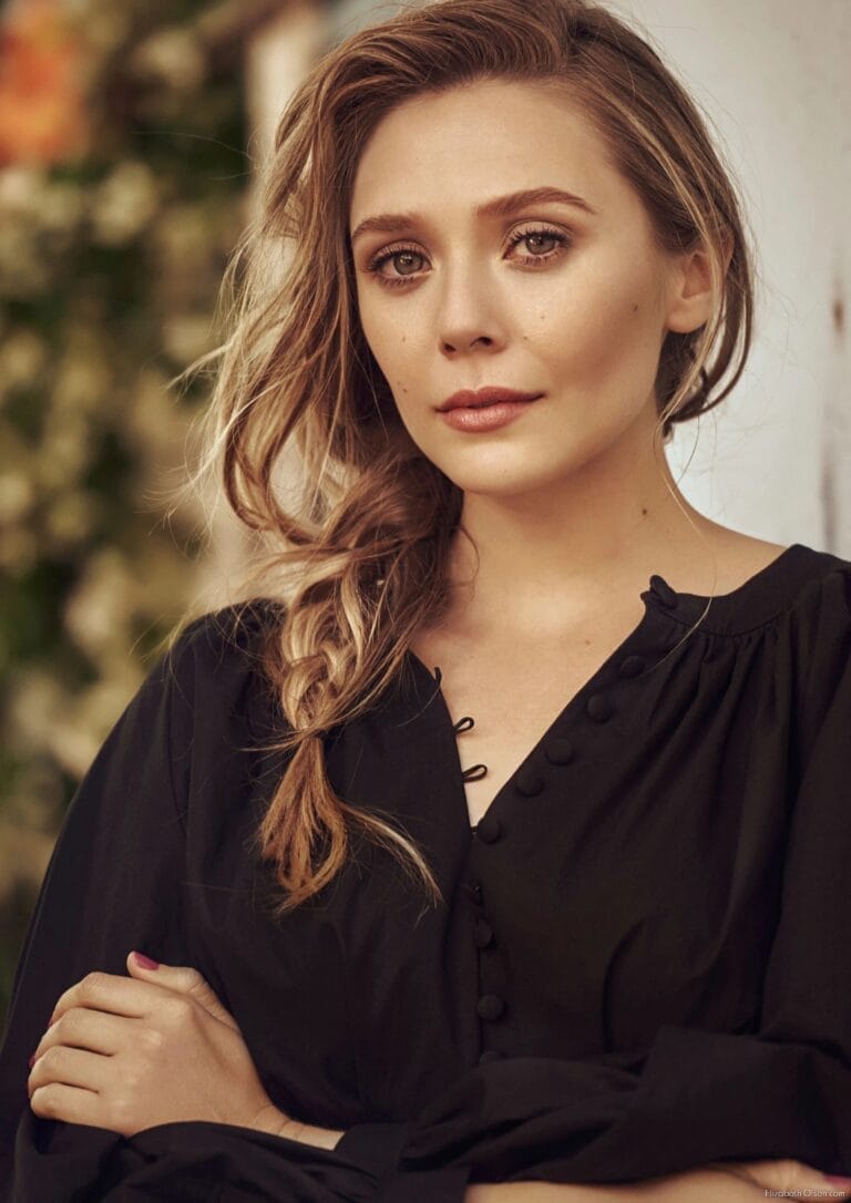 Elizabeth Olsen: Wears a black blouse with decorative buttons. Hair styled in a braid…