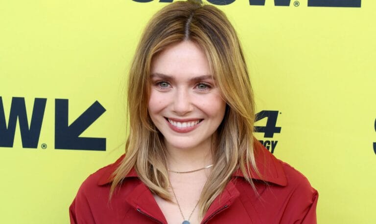 Elizabeth Olsen: Wears a red jacket and delicate necklaces. The background is yellow with…