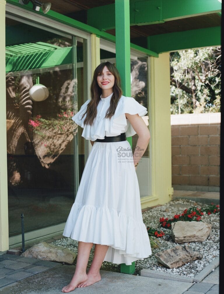 Elizabeth Olsen: Wears a white dress with ruffles and a dark belt that highlights her figure.…