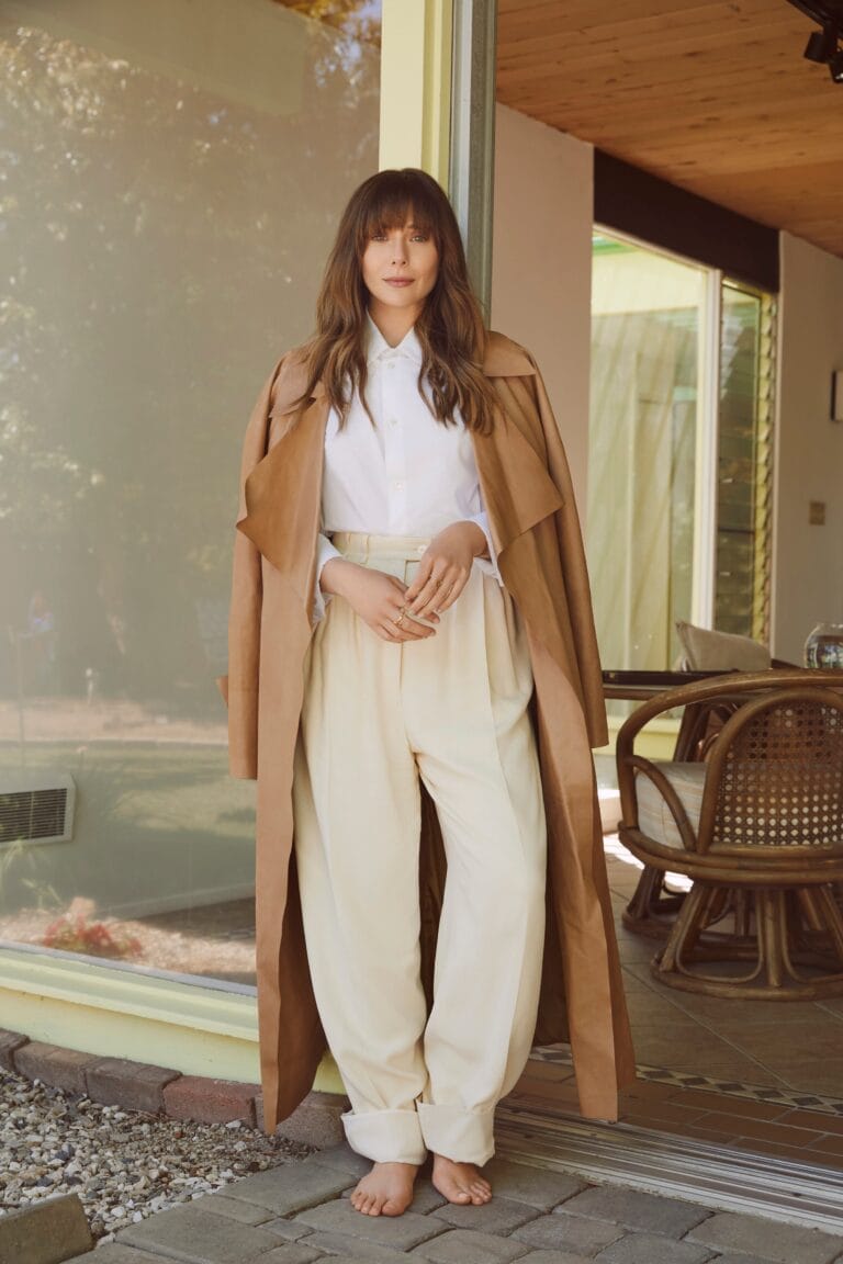 Elizabeth Olsen: Wears a long camel coat over a white button-up shirt and pants…