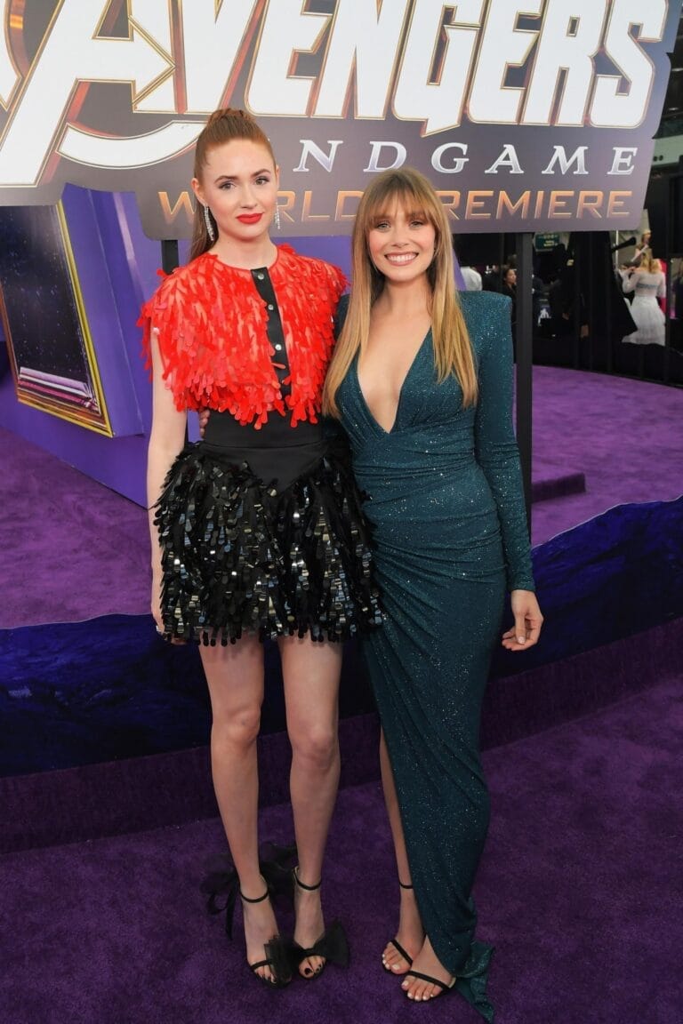 Elizabeth Olsen: Wears a red and black dress, full of 3D details, and sandals…