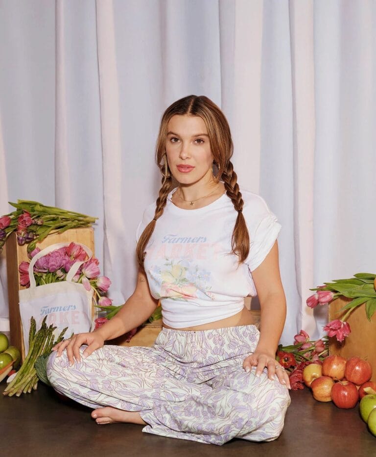 Millie Bobby Brown: Wearing a white T-shirt with a floral design and loose pants with a pattern…