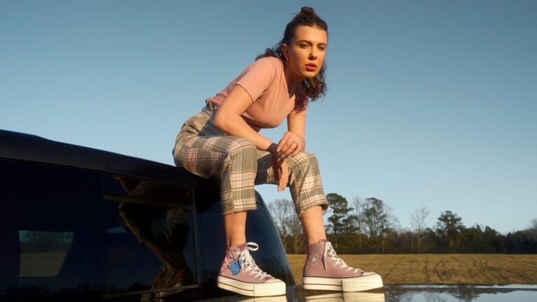 Millie Bobby Brown: Wears a pink T-shirt and plaid pants. Lilac high-top sneakers…